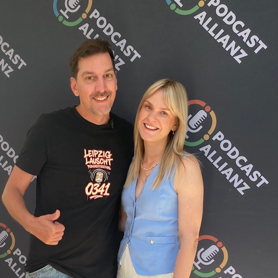 Zwei Personen vor der Fotowand der Podcast Allianz